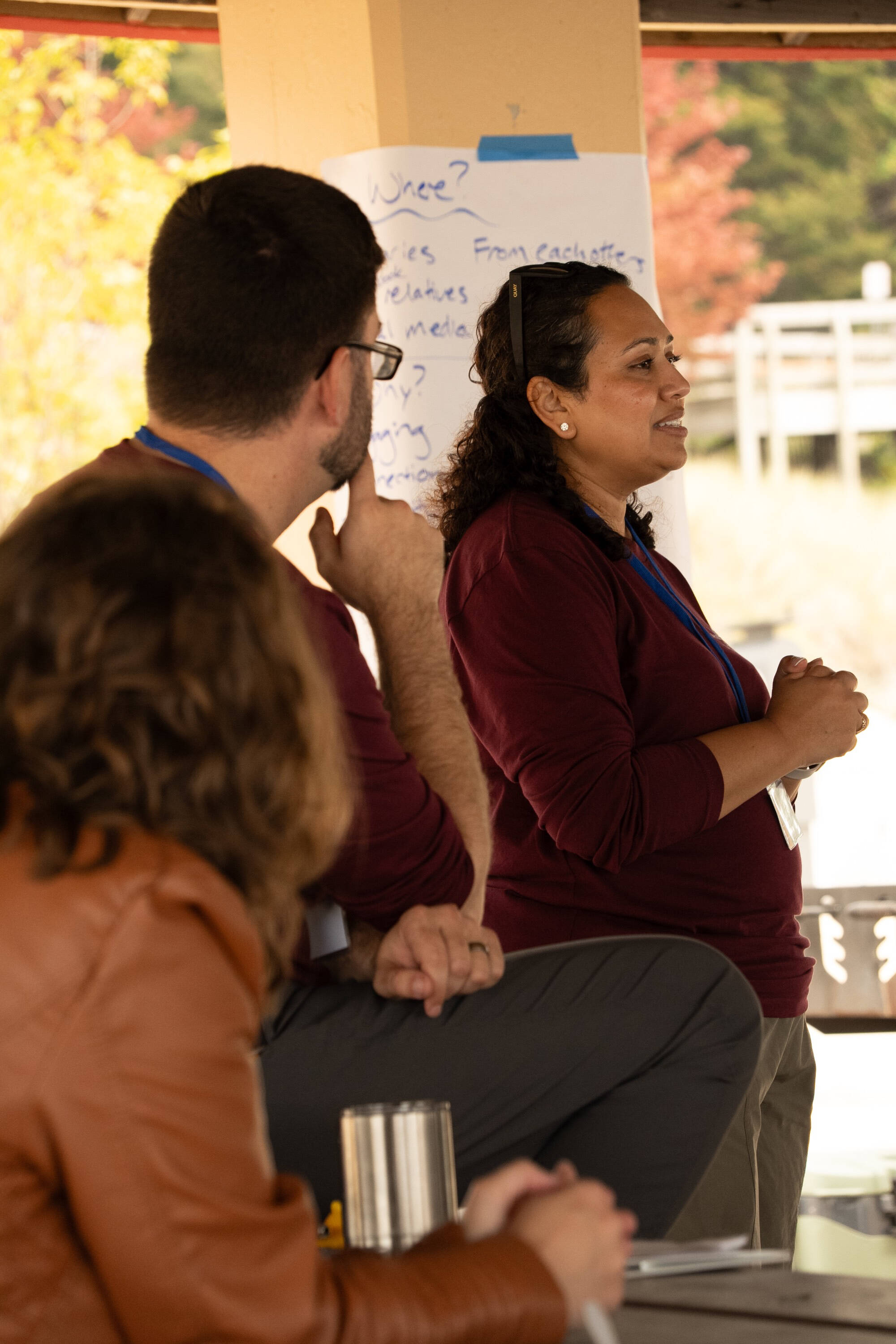 A woman in focus in the background leading discussion with two people in the foreground.
